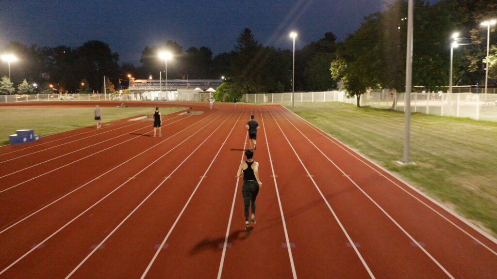 Athletics Track LED Floodlight on a Dark Night with Athletes running on Track